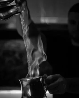 Bartender pouring a steaming Morning on the Platform cocktail